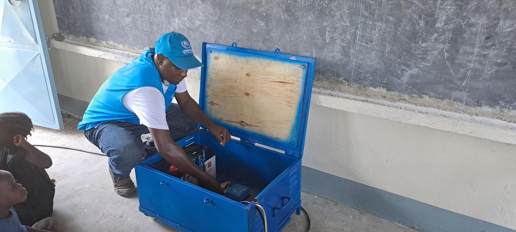 John Paul Ojok attending to the solar power box